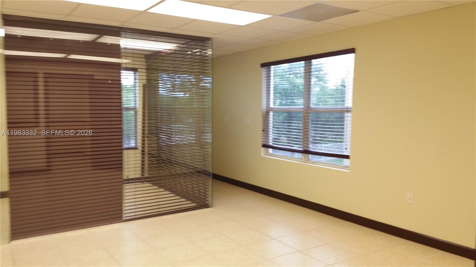 An office space features light-colored tile flooring, pale yellow walls, and a glass-partitioned room — 11980 SW 144th Ct # 206, Miami FL 33186, MIAMI, FL