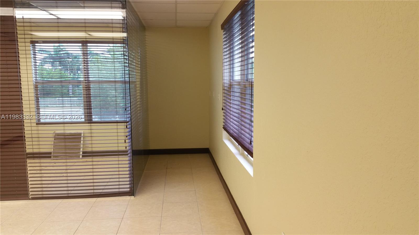 An empty office space features tile flooring, beige walls, and windows with brown blinds — 11980 SW 144th Ct # 206, Miami FL 33186, MIAMI, FL
