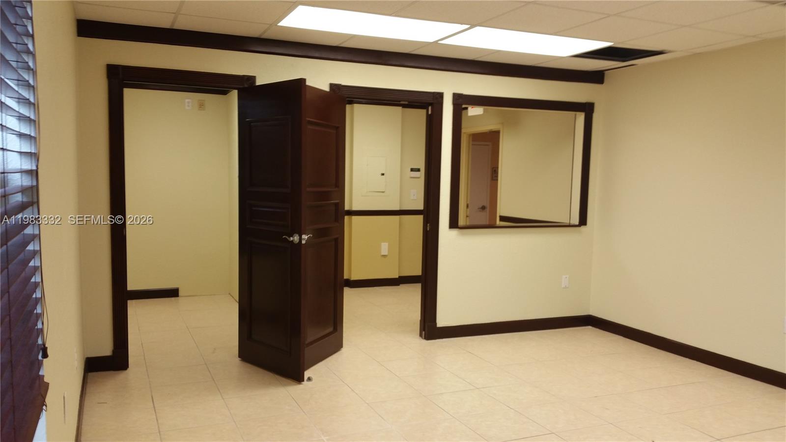An office space features light-colored tile flooring, dark wood trim, and an open doorway — 11980 SW 144th Ct # 206, Miami FL 33186, MIAMI, FL