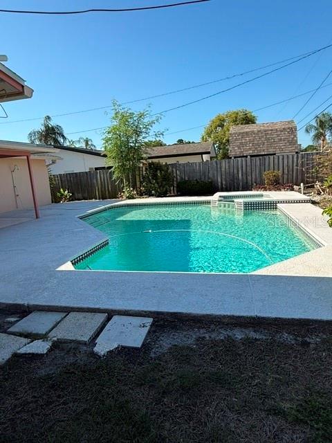 A backyard features a rectangular swimming pool with a concrete deck and a wooden fence — 1884 YALE DRIVE, CLEARWATER, FL