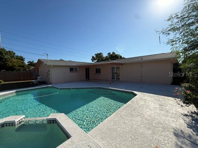 A backyard features a swimming pool with an attached spa and a light-colored house exterior — 1884 YALE DRIVE, CLEARWATER, FL