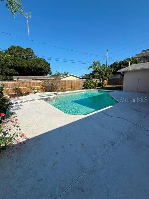A backyard features a rectangular swimming pool with a concrete deck and a wooden fence — 1884 YALE DRIVE, CLEARWATER, FL