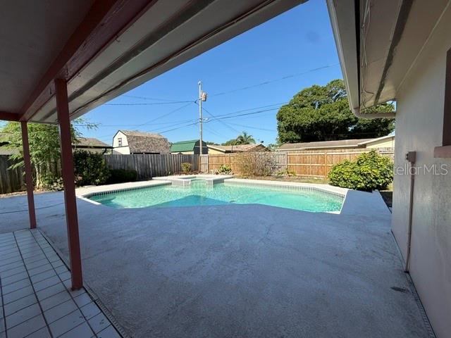 A view from a covered patio looking out toward a backyard swimming pool and fence — 1884 YALE DRIVE, CLEARWATER, FL