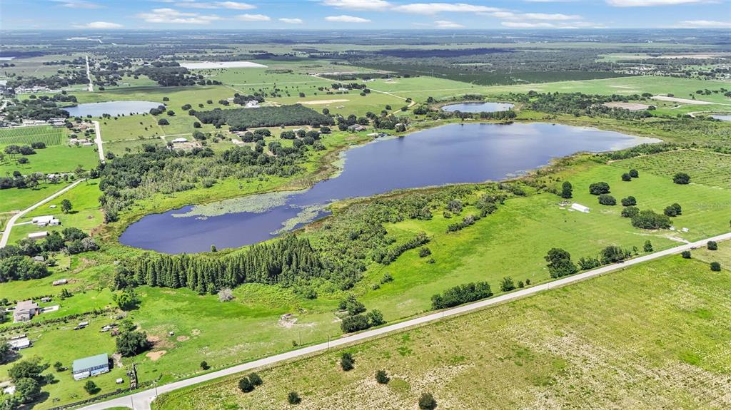 An aerial view shows a large lake surrounded by green pastures, trees, and rural roads — 8450 ALTURAS BABSON PARK CUTOFF ROAD, BARTOW, FL