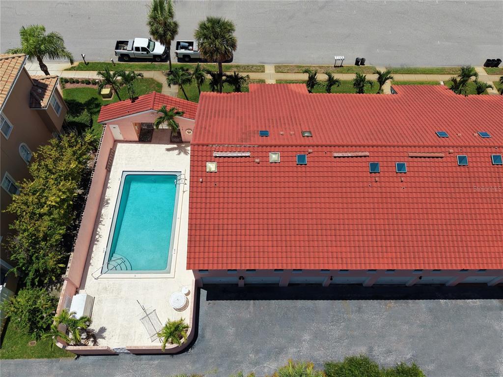 An aerial view shows a red-tiled roof building with an adjacent swimming pool and patio — 357 8TH AVENUE N UNIT 4, TIERRA VERDE, FL