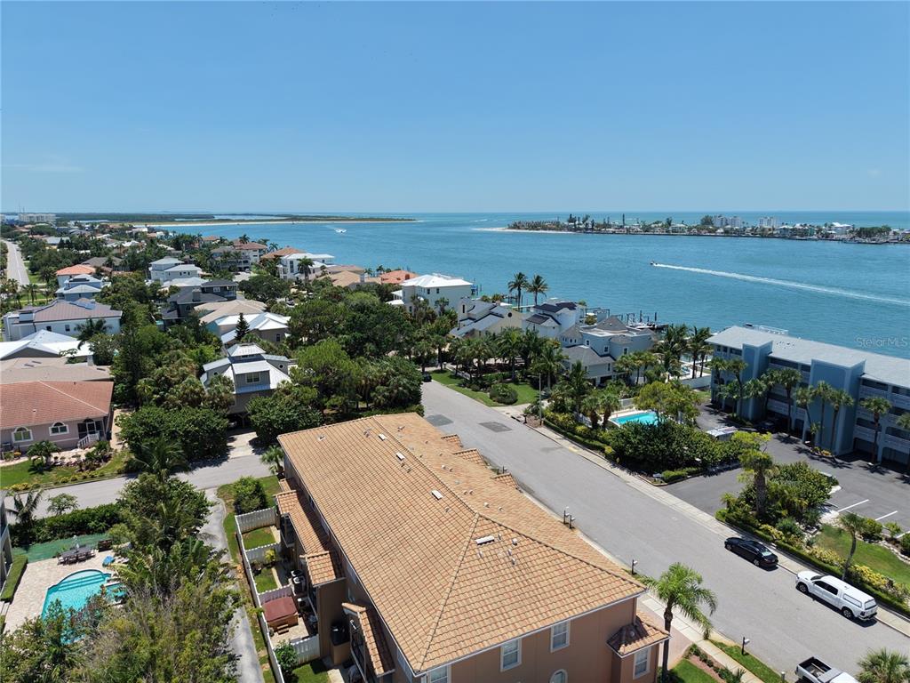 An aerial view shows a multi-story residential building near a coastal waterway and homes — 357 8TH AVENUE N UNIT 4, TIERRA VERDE, FL
