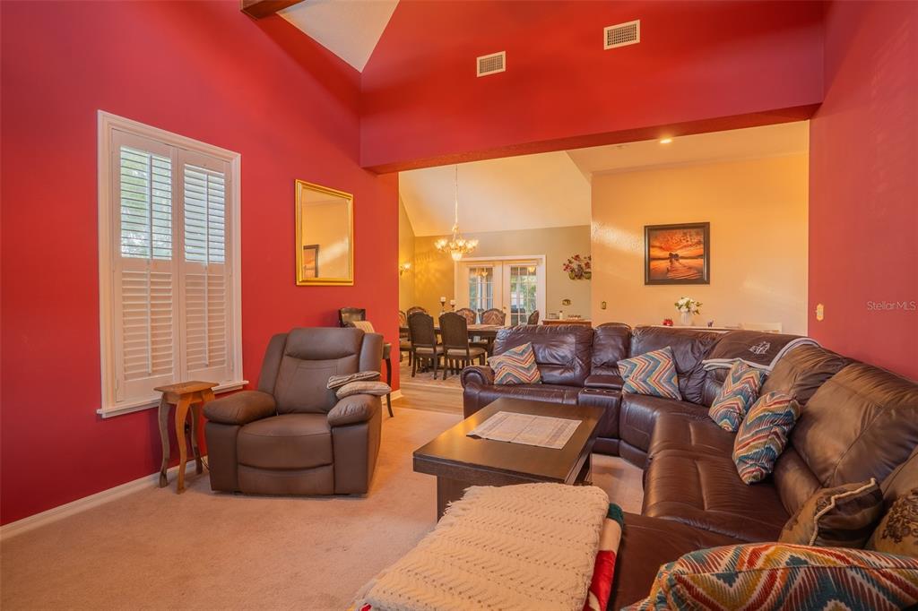 A living room with red walls, a brown leather sectional, and a recliner — 1415 PIER COURT, LAKELAND, FL