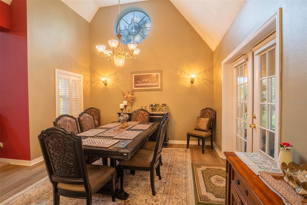 A dining room features a vaulted ceiling, a chandelier, and a glass-topped table with chairs — 1415 PIER COURT, LAKELAND, FL