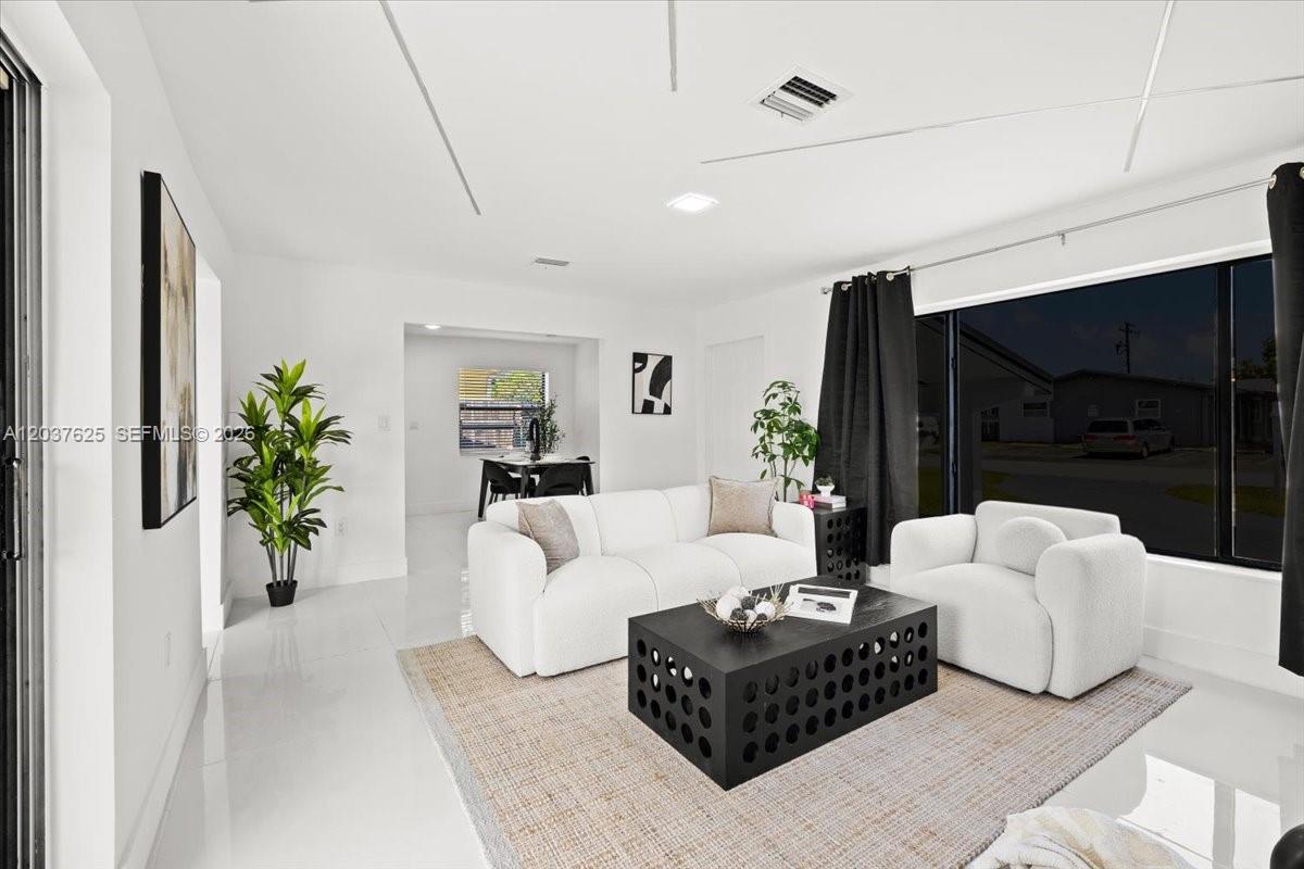 A living room features white furniture, a black coffee table, and a large window — 7500 Venetian St, Miramar FL 33023, MIRAMAR, FL