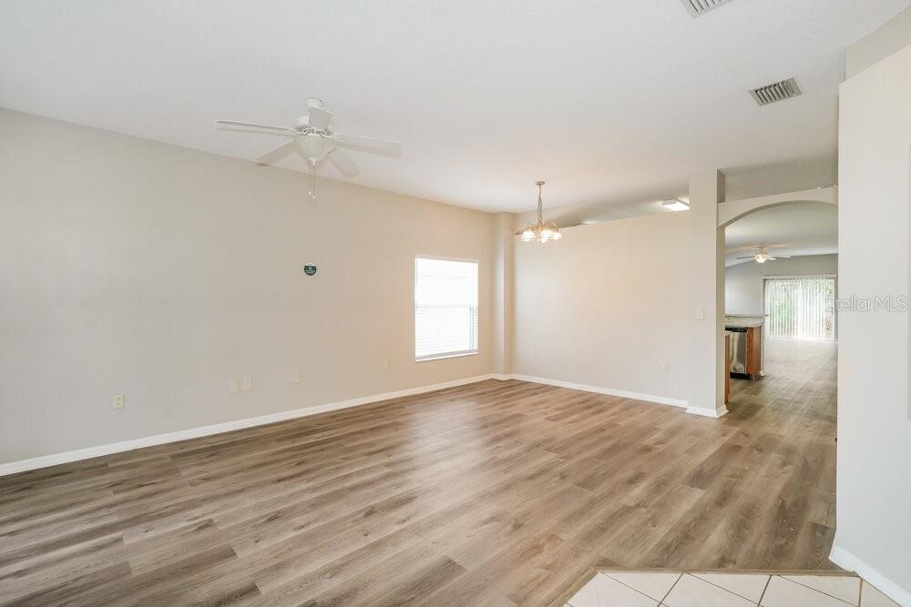 An empty living room features light-colored walls, wood-look flooring, and a ceiling fan — 5310 BRADDOCK DRIVE, ZEPHYRHILLS, FL