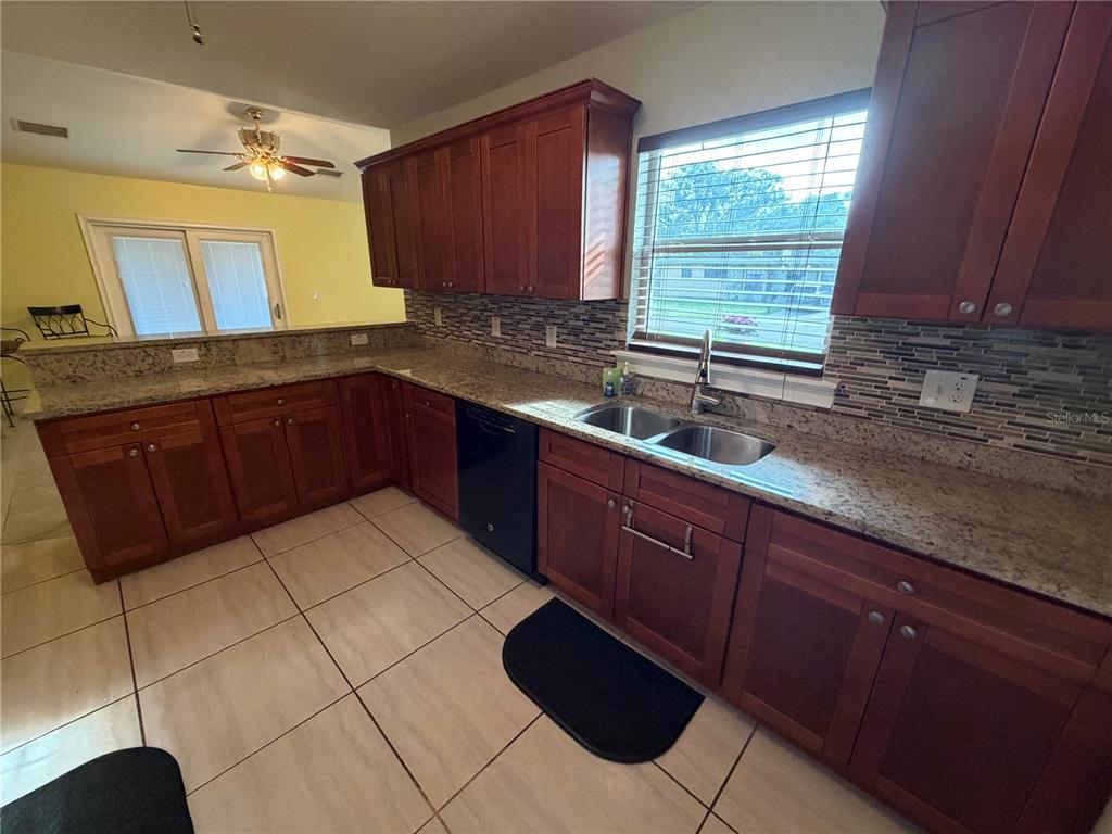 A kitchen features wood cabinets, granite countertops, a tile floor, and a double sink — 1131 DOGWOOD AVENUE, TAMPA, FL
