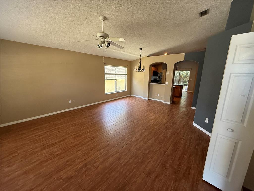 An open-concept living room features wood-look tile flooring, a ceiling fan, and a dining area — 10536 RODONDO DRIVE, ORLANDO, FL