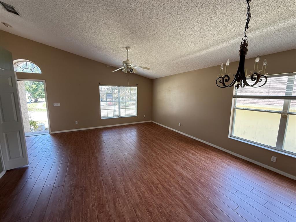 A living room with wood-look tile flooring, a ceiling fan, and a chandelier — 10536 RODONDO DRIVE, ORLANDO, FL