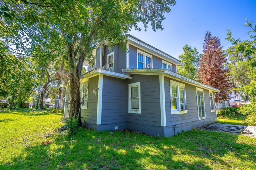 A two-story house with gray horizontal siding and white trim stands in a grassy yard — 1419 KING STREET, KISSIMMEE, FL