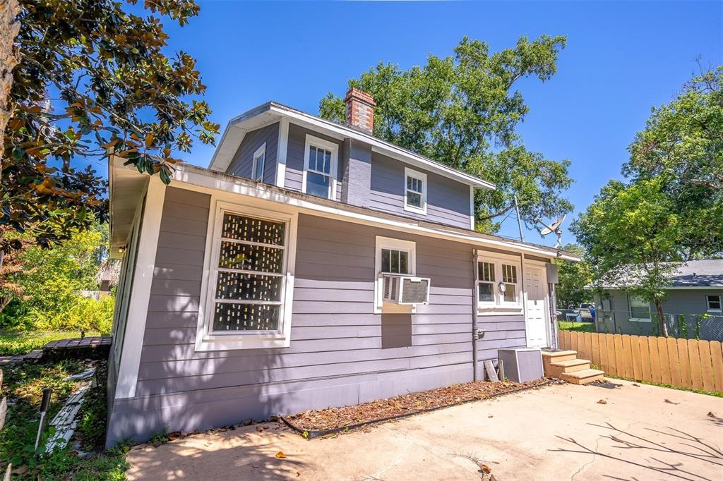 The exterior of a two-story gray house features a concrete patio and a wooden fence — 1419 KING STREET, KISSIMMEE, FL