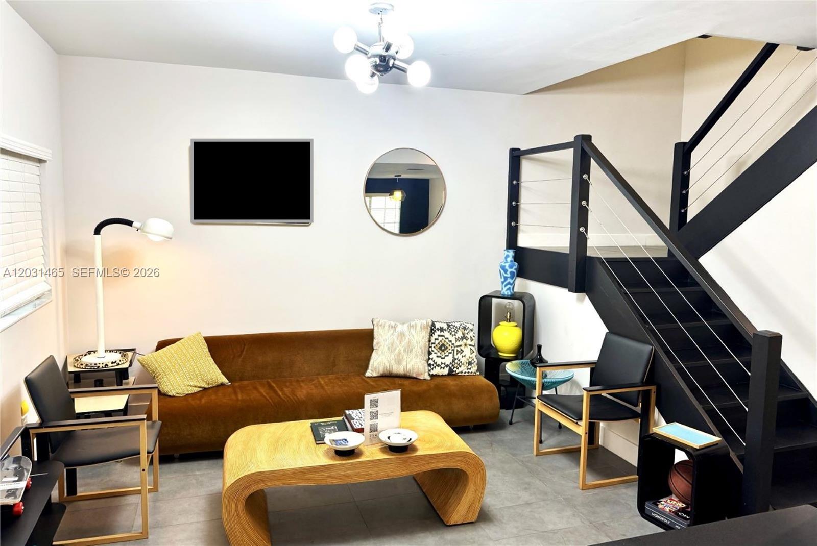 A living room features a brown sofa, a wooden coffee table, and a black staircase — 360 NW 19th Ter # 58, Miami FL 33136, MIAMI, FL