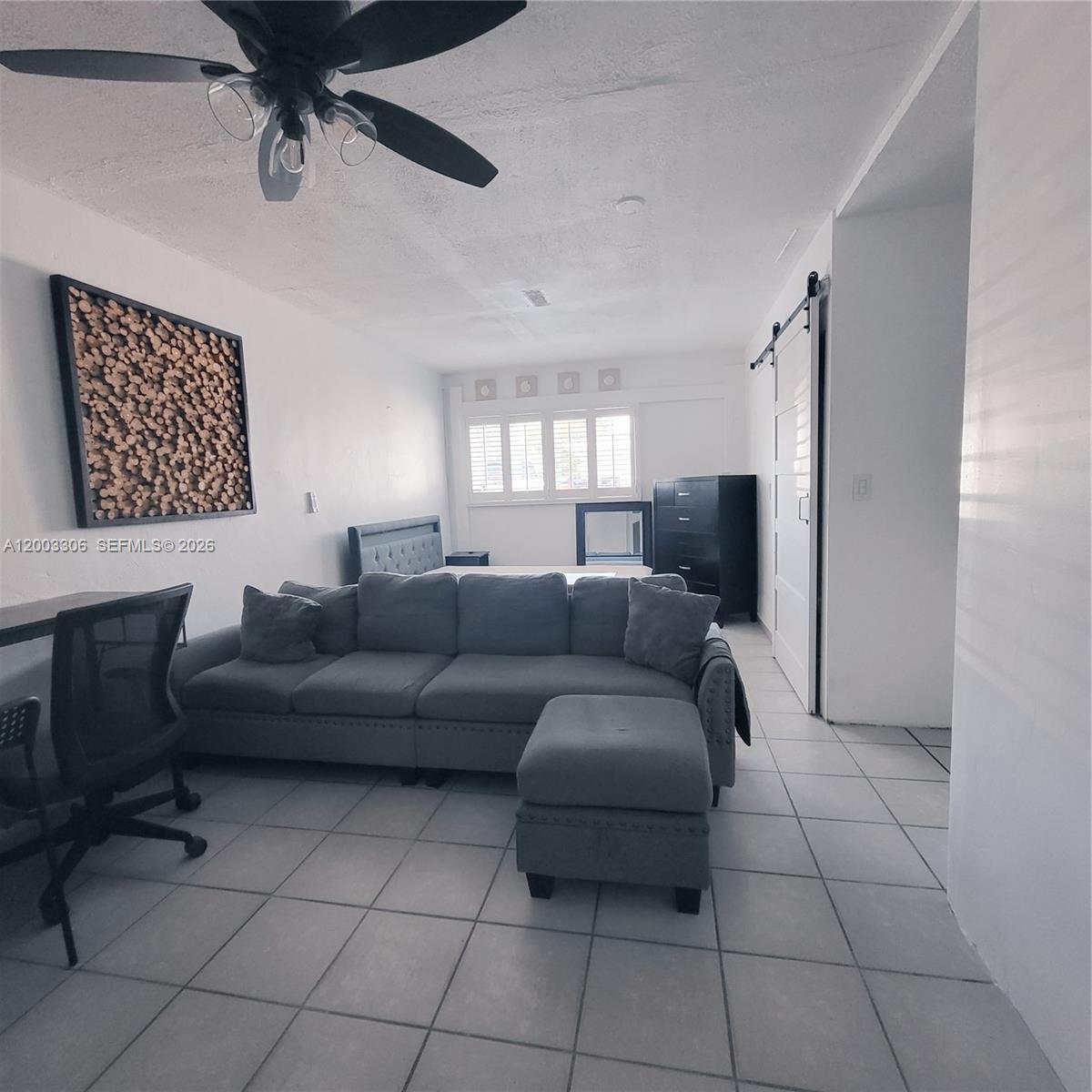 This studio apartment features a gray sectional sofa, a bed, and tiled flooring — 3405 W Lake Pl # 1, Miramar FL 33023, MIRAMAR, FL