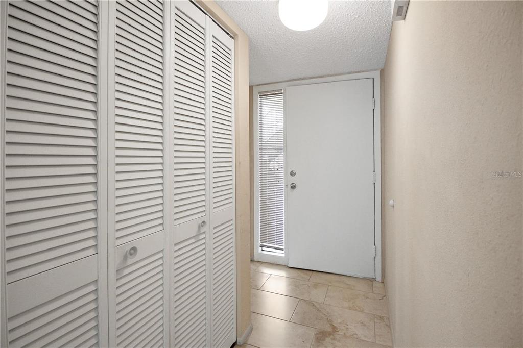 An entryway features white louvered closet doors, a white front door, and tiled flooring — 135 WOODLAKE WYNDE UNIT 135, OLDSMAR, FL