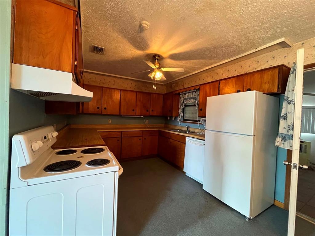 A kitchen with wood cabinets, white appliances, and a ceiling fan over a linoleum floor — 688 AIROSO ROAD SE, PALM BAY, FL