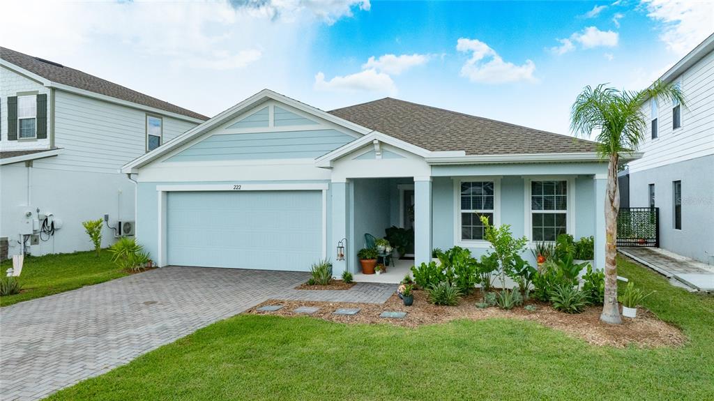 A light blue single-story house features a two-car garage and a landscaped front yard — 222 EAGLE HARBOR WAY, DAYTONA BEACH, FL