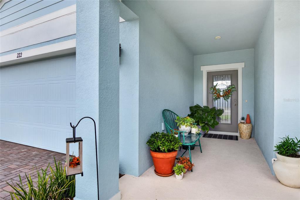 A light blue house exterior features a front porch with potted plants and a bench — 222 EAGLE HARBOR WAY, DAYTONA BEACH, FL