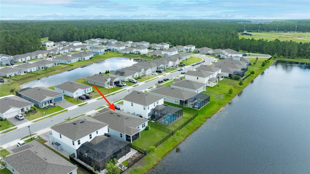 An aerial view shows a suburban neighborhood with houses, a pond, and a red arrow — 222 EAGLE HARBOR WAY, DAYTONA BEACH, FL