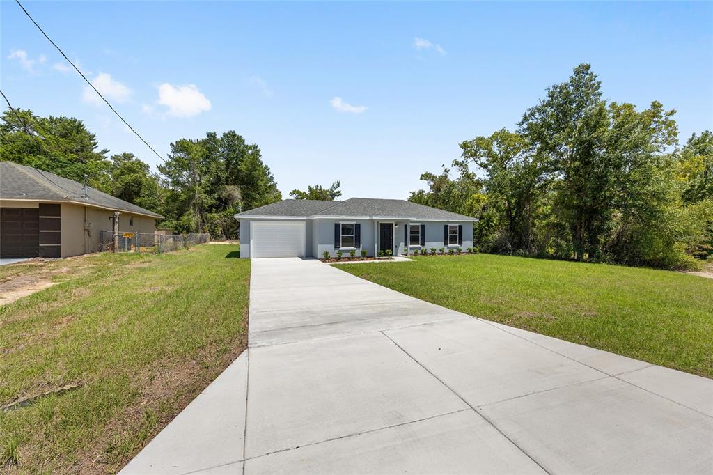 A single-story house with a gray exterior, white garage door, and a concrete driveway — 29 OLIVE CIRCLE, OCALA, FL