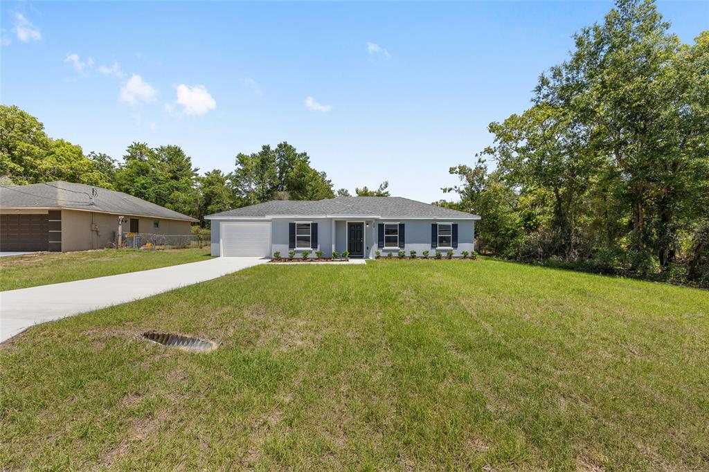 A single-story house with a gray exterior, white garage, and a large front lawn — 29 OLIVE CIRCLE, OCALA, FL