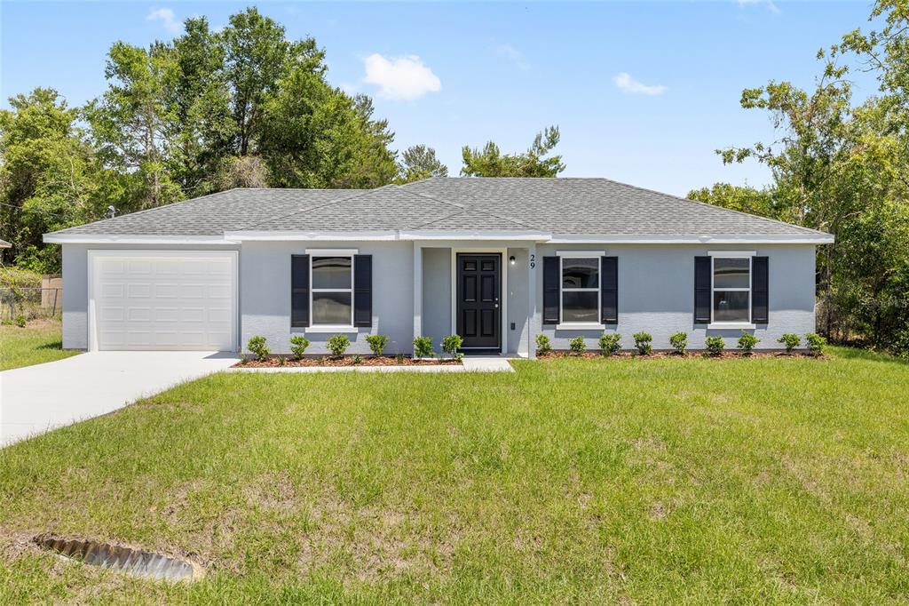 A single-story gray house with a garage, black shutters, and a front lawn — 29 OLIVE CIRCLE, OCALA, FL