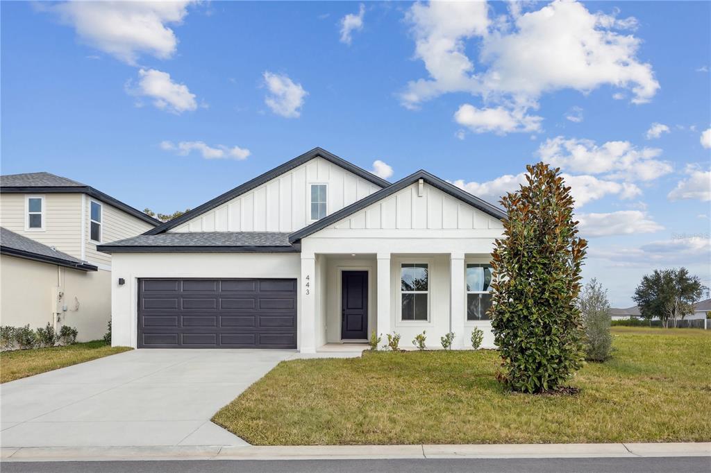A single-story white house with a dark garage door and a covered front porch — 86 SPRINGWOOD DRIVE, PALM COAST, FL