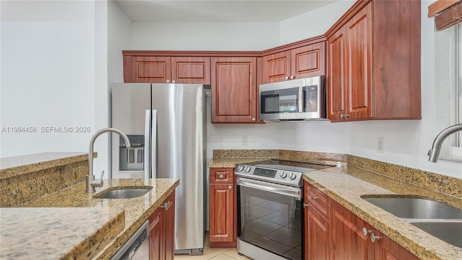 A kitchen features cherry wood cabinets, granite countertops, and stainless steel appliances — 6002 SW 8th St # 3, West Miami FL 33144, WEST MIAMI, FL