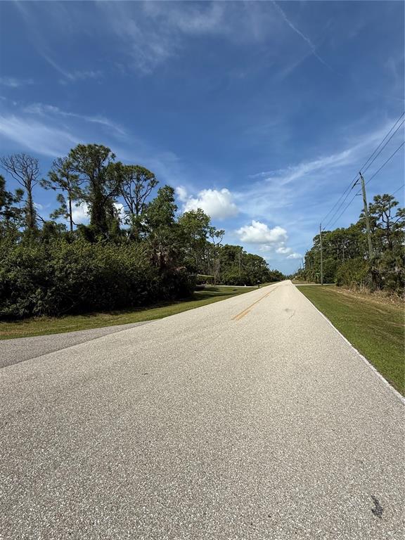 A paved road stretches into the distance, flanked by trees and utility poles under a sky — 5101 HOPKINS AVENUE, PORT CHARLOTTE, FL