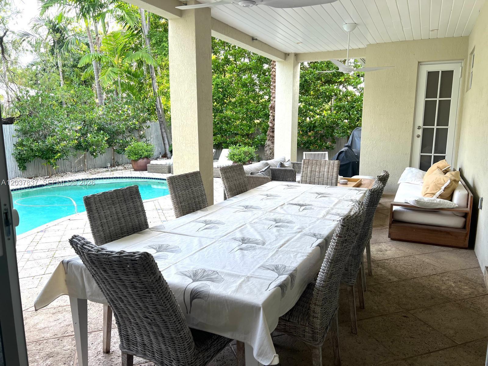 A covered outdoor patio features a dining table, wicker chairs, and a swimming pool — 797 Glenridge Rd, Key Biscayne FL 33149, KEY BISCAYNE, FL