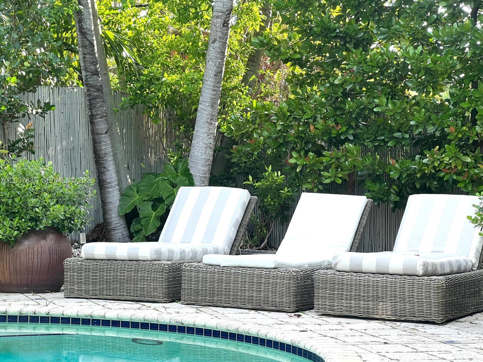 Three wicker lounge chairs with striped cushions sit on a patio beside a swimming pool — 797 Glenridge Rd, Key Biscayne FL 33149, KEY BISCAYNE, FL