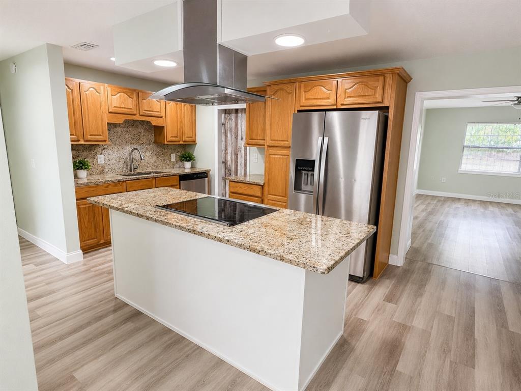 A kitchen features oak cabinets, granite countertops, a center island with a cooktop, and stainless appliances — 632 MAYS COURT, ORLANDO, FL