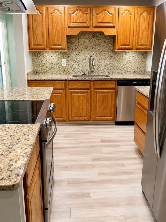 A kitchen features oak cabinets, granite countertops, a stainless steel stove, and light wood flooring — 632 MAYS COURT, ORLANDO, FL