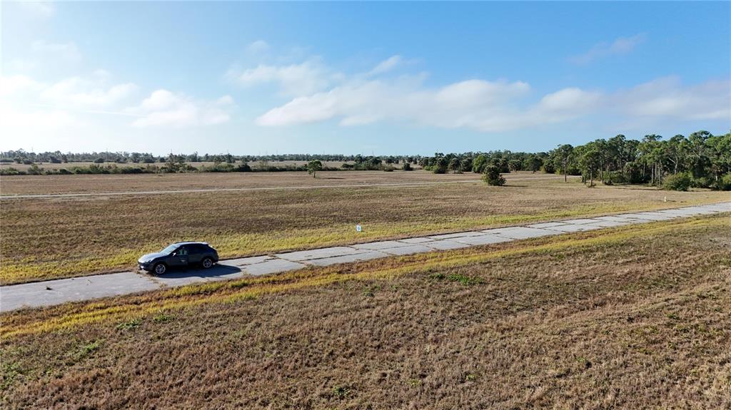 An aerial view shows a dark SUV parked on a paved road through a field — 14260 BLUEFISH COURT, PLACIDA, FL