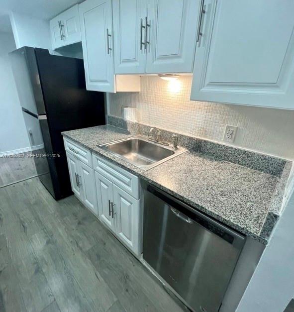 A kitchen features white cabinets, granite countertops, a stainless steel dishwasher, and a black refrigerator — 4501 W Mcnab Rd # 10, Pompano Beach FL 33069, POMPANO BEACH, FL