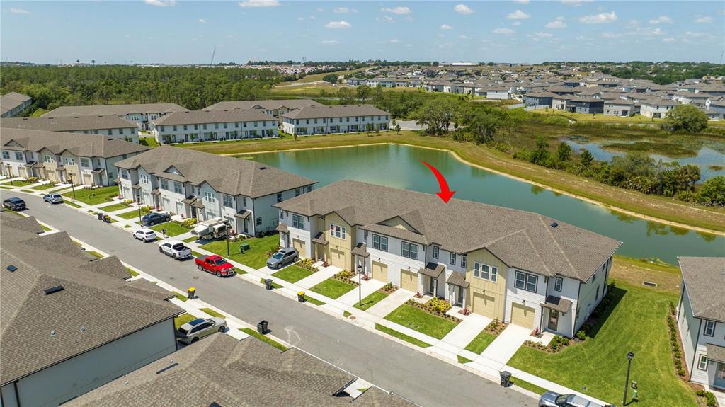An aerial view shows a row of townhouses situated next to a small pond — 686 LONGBOAT DRIVE, DAVENPORT, FL