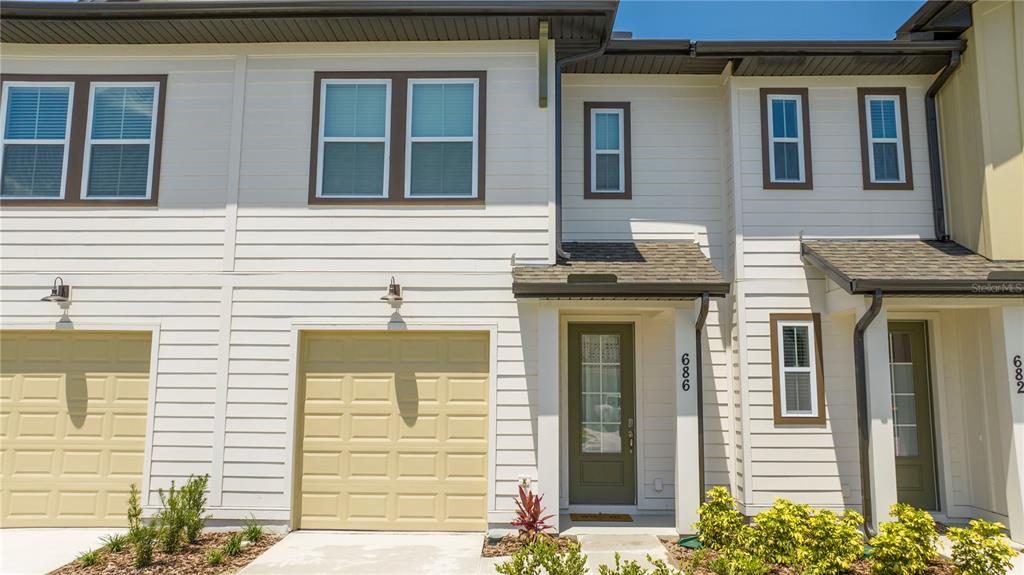 A two-story townhouse exterior features light siding, a single-car garage, and a front entrance — 686 LONGBOAT DRIVE, DAVENPORT, FL