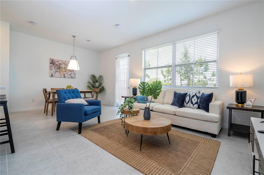 A bright living and dining area features tile floors, a neutral sofa, and blue accents — 686 LONGBOAT DRIVE, DAVENPORT, FL