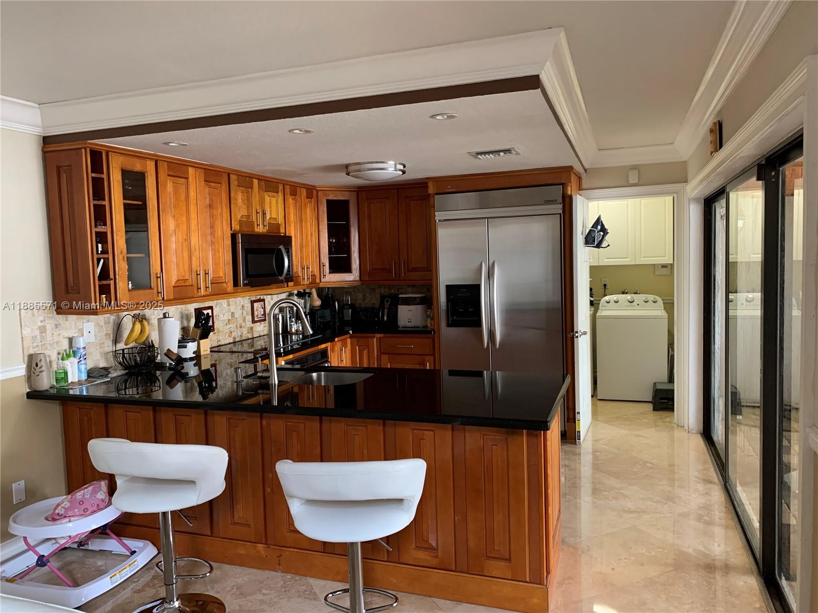 A kitchen features wood cabinetry, black granite countertops, stainless steel appliances, and a breakfast bar — 10115 NW 4th Ln # 8, Miami FL 33172, MIAMI, FL
