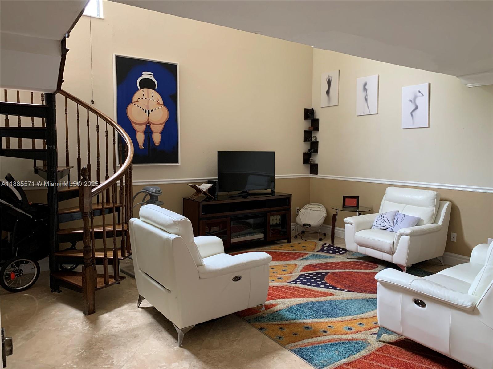 A living room features a spiral staircase, white leather armchairs, and a colorful area rug — 10115 NW 4th Ln # 8, Miami FL 33172, MIAMI, FL