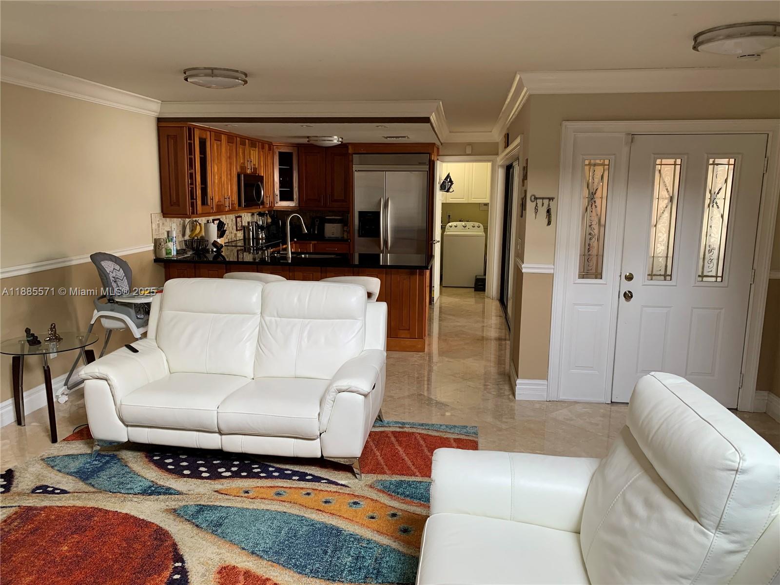 A living room with white leather sofas and a colorful rug faces an open kitchen — 10115 NW 4th Ln # 8, Miami FL 33172, MIAMI, FL