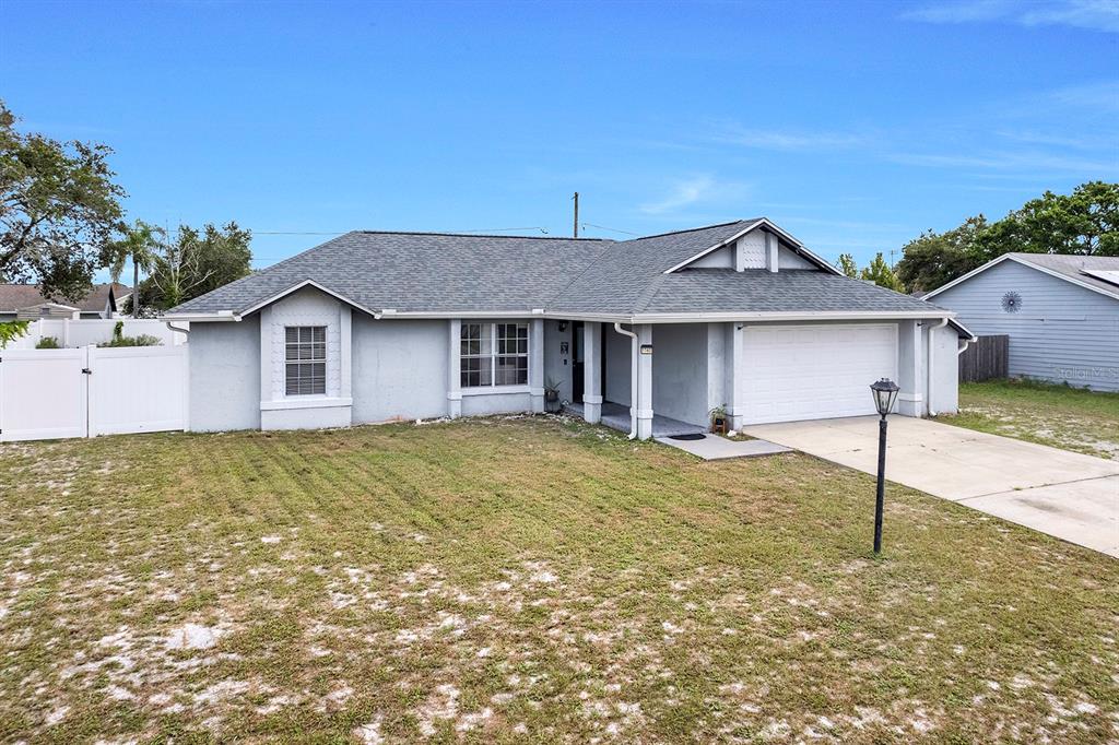 A single-story house with a gray exterior, a two-car garage, and a large front lawn — 1160 MANITOBA STREET, DELTONA, FL