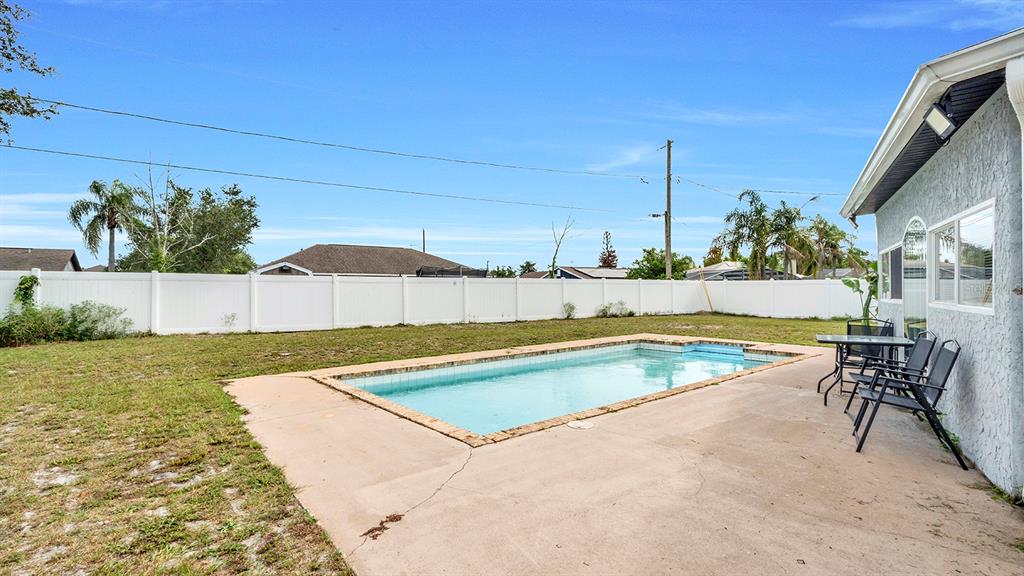 A backyard features a rectangular swimming pool, a concrete patio, and a white privacy fence — 1160 MANITOBA STREET, DELTONA, FL