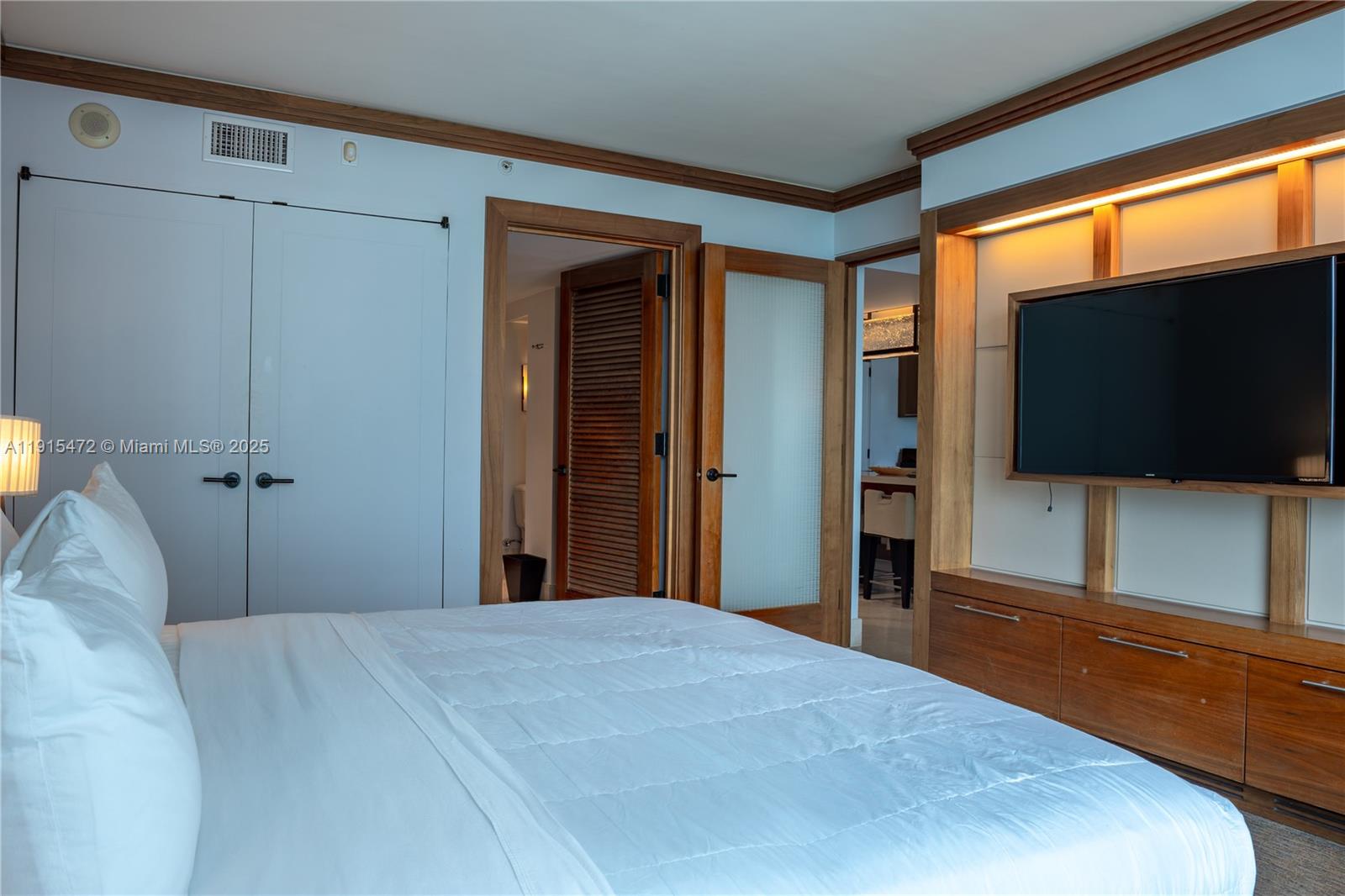A bedroom features a bed, a wall-mounted television, and two doorways leading to other rooms — 6801 Collins Ave # 1002, Miami Beach FL 33141, MIAMI BEACH, FL