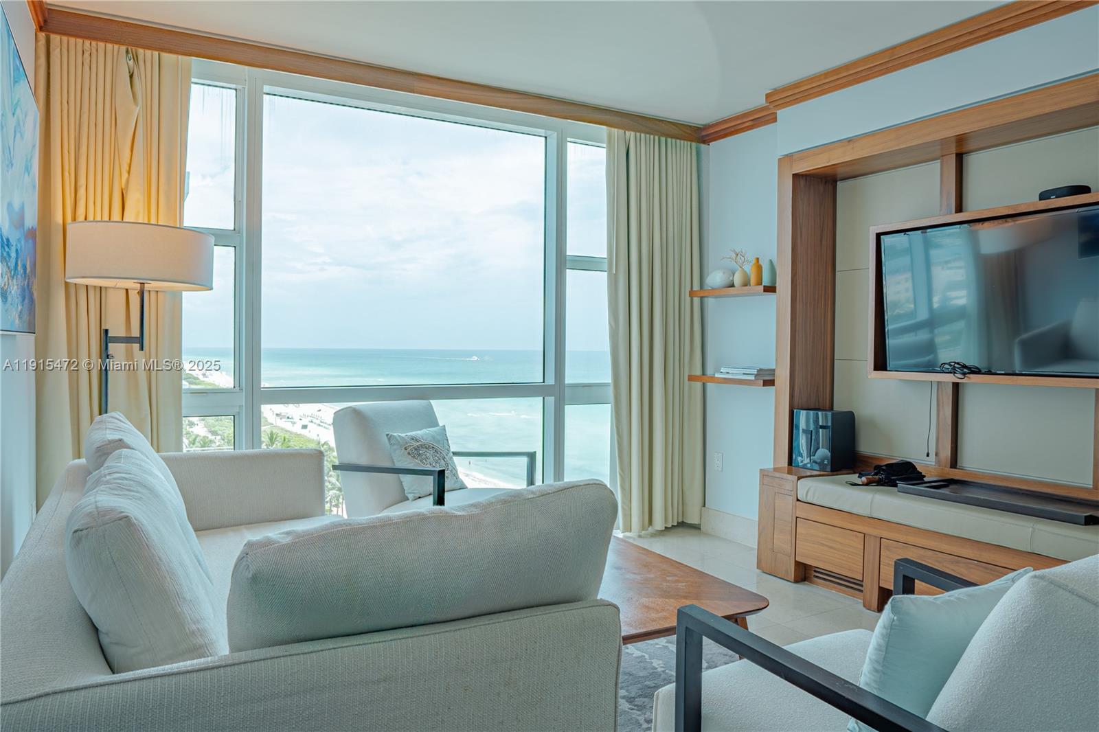 A living room features a sofa, armchairs, and a large window overlooking the ocean — 6801 Collins Ave # 1002, Miami Beach FL 33141, MIAMI BEACH, FL