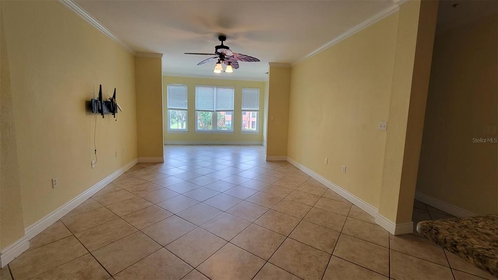 An empty room with yellow walls, tile flooring, and a ceiling fan — 2713 VIA MURANO UNIT 221, CLEARWATER, FL