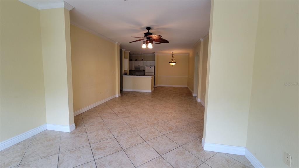 An open-concept living and dining area features light yellow walls and beige tile flooring — 2713 VIA MURANO UNIT 221, CLEARWATER, FL